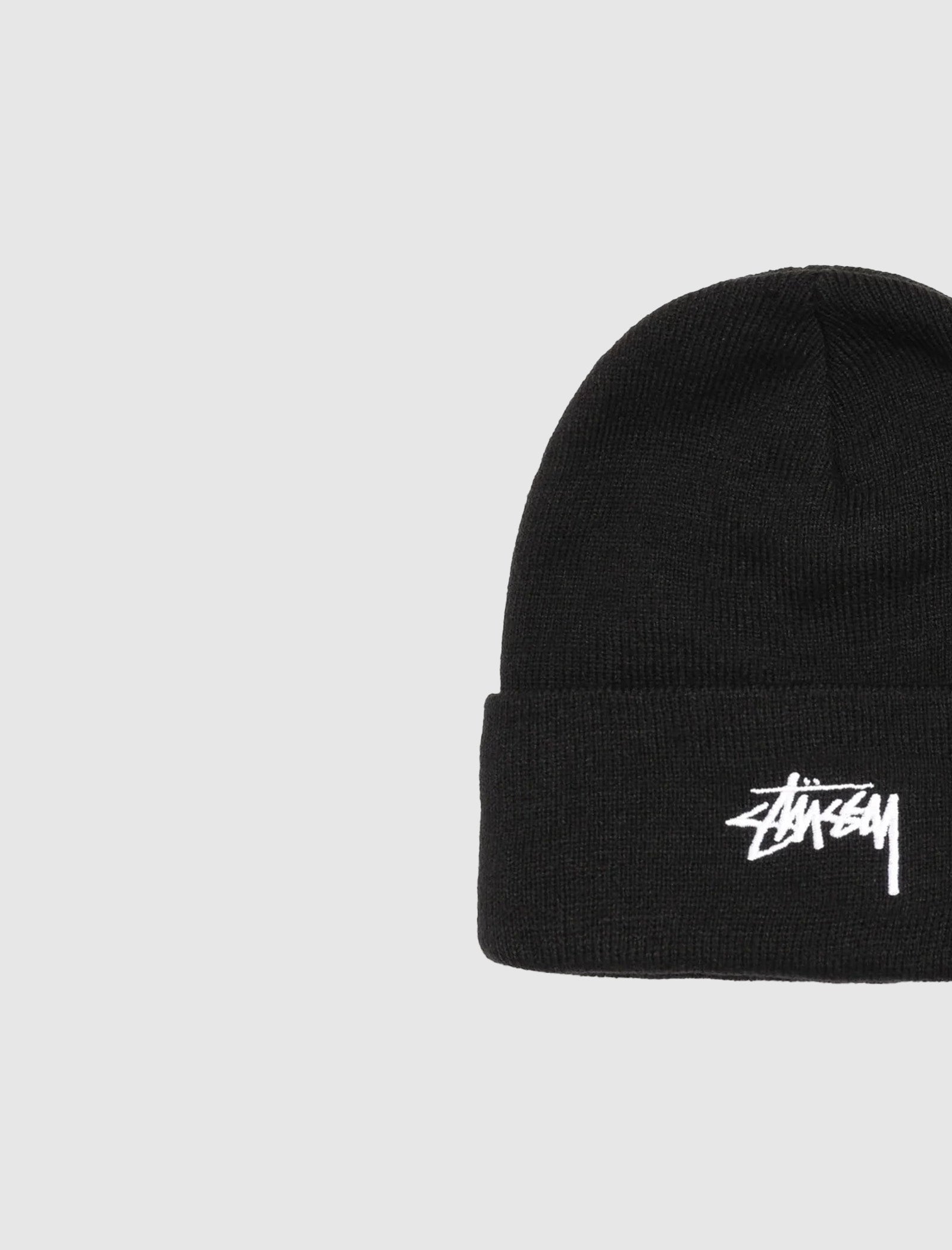 The STOCK CUFF BEANIE is a black cuff beanie with a folded brim and white embroidered Stüssy logo, displayed against a plain light gray background.