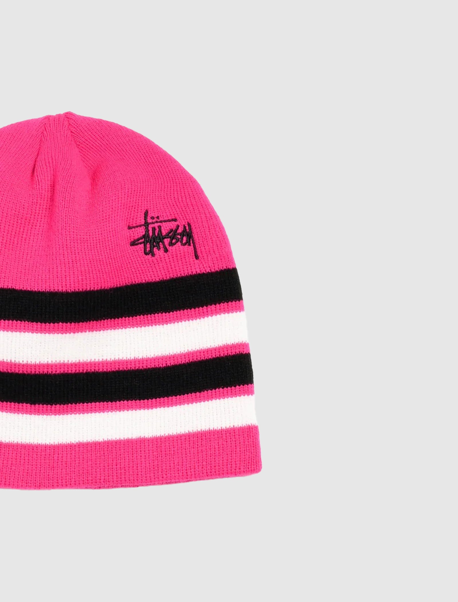 The SKULLCAP STRIPED is a bright pink beanie with horizontal black and white stripes and a black embroidered logo on the front, shown against a light grey background. This stylish knit skullcap adds a bold touch to any outfit.