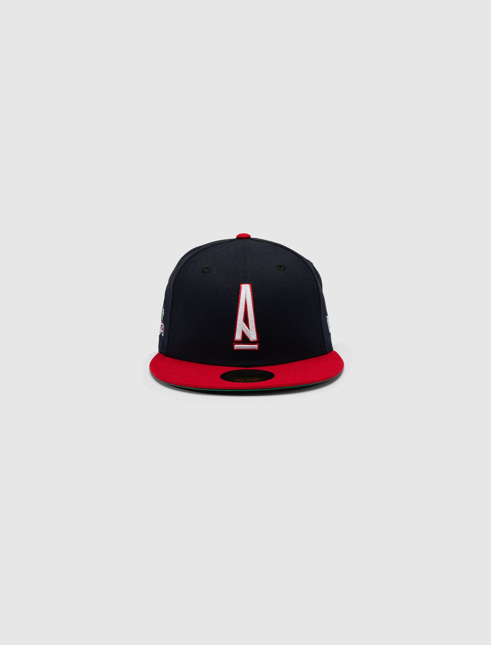 The A MA MANIÉRE 5950 A LOGO HAT by New Era features a black crown, vibrant red brim, and bold white and red "A" logo on the front, set against a plain light gray background.