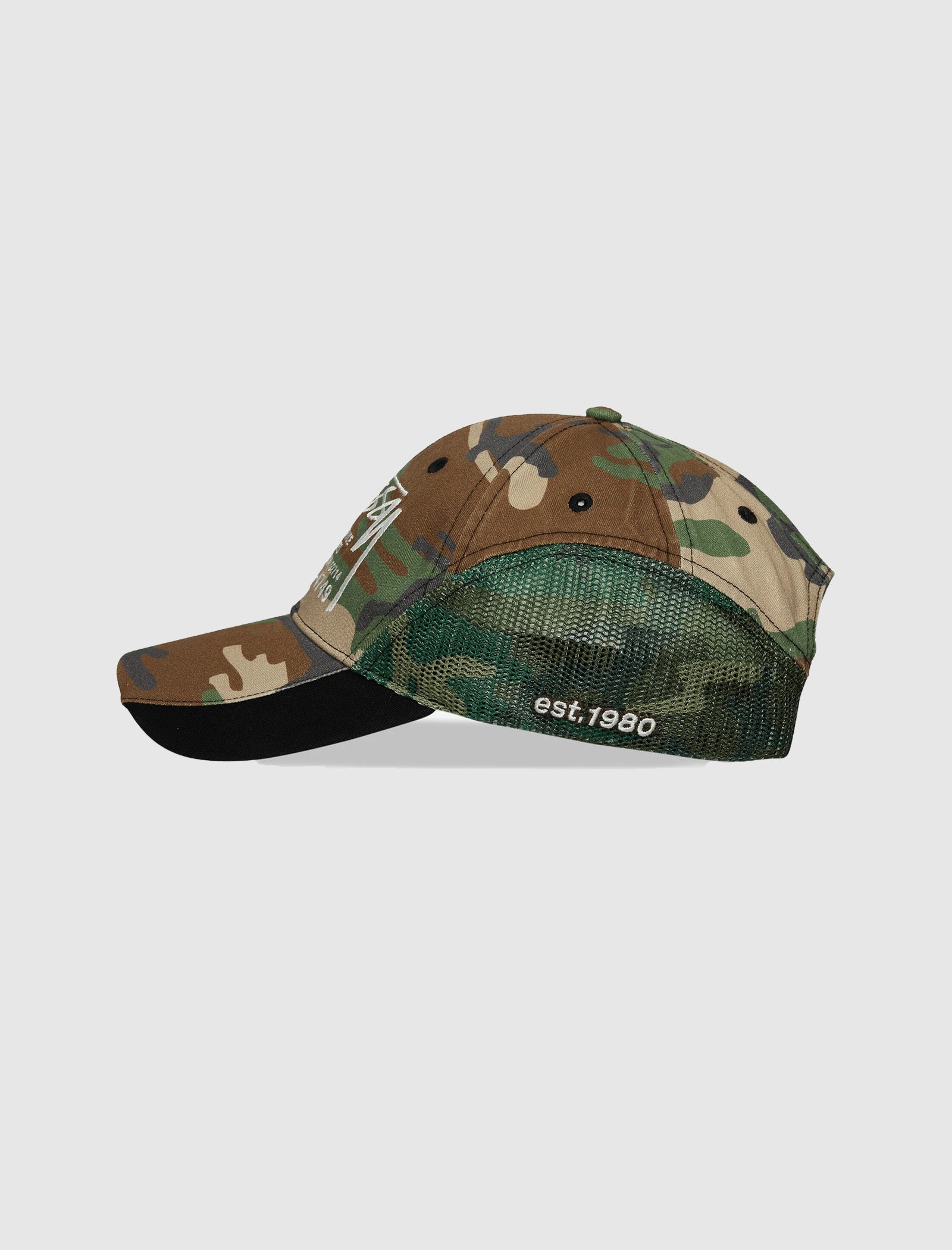 The LOW PROFILE SERVICE MESH STRAPBACK CAP features a camo print, green mesh back, "est. 1980" in white embroidery on the side, and an adjustable snapback closure. Shown against a plain light background.