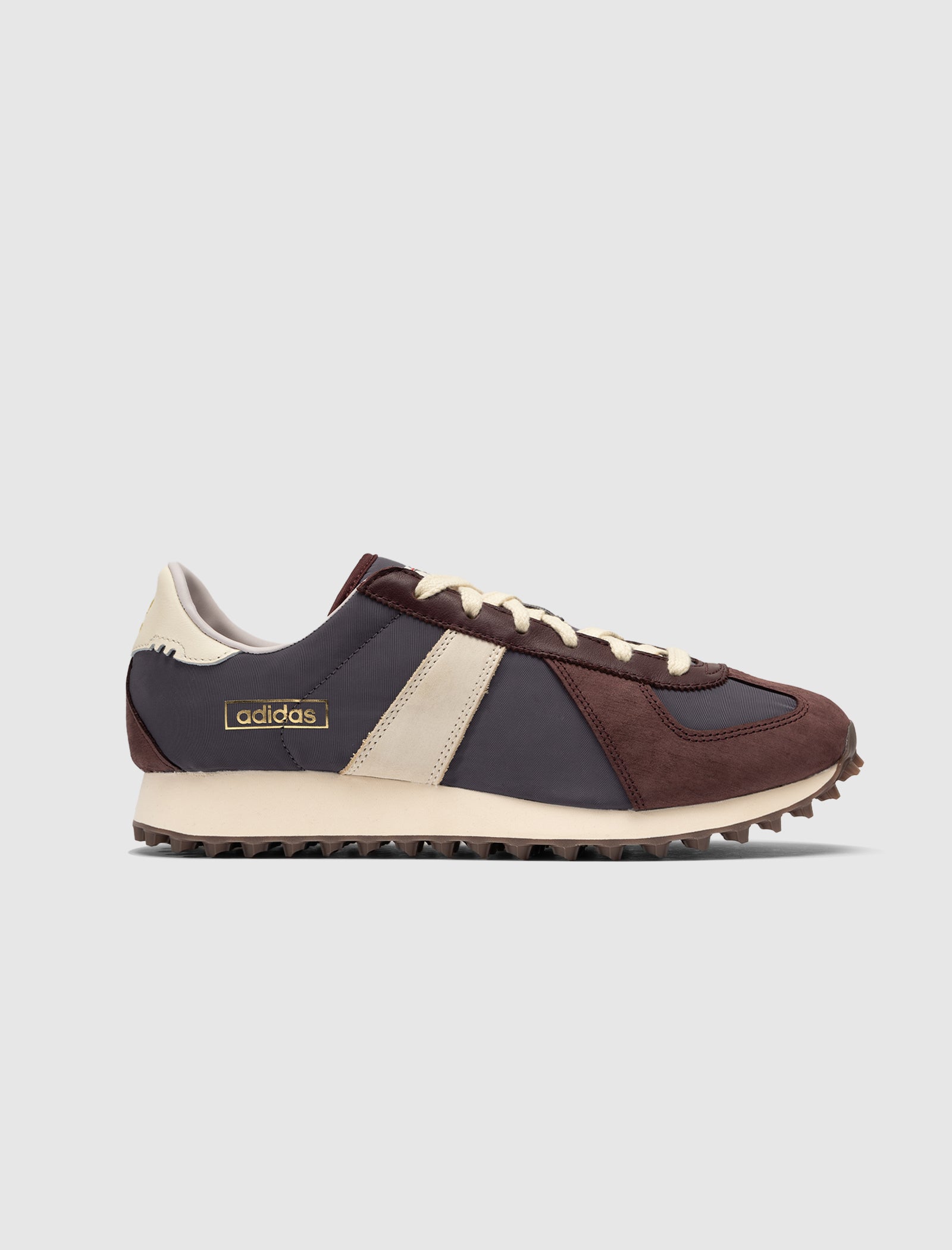 A side view of the DND BW RUN HARLEM'S BEST Adidas low top sneakers in dark brown, navy, and cream with a cream stripe, cream laces, jagged sole, and suede accents, set against a plain light gray background.