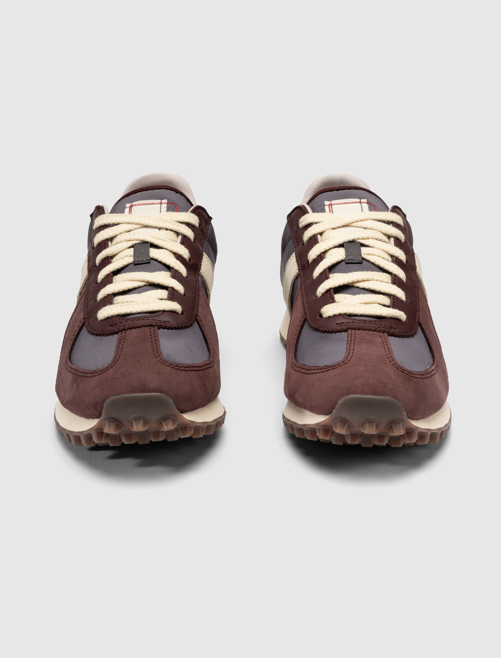 The DND BW RUN HARLEM'S BEST sneakers in brown and gray feature white laces and suede accents, shown from the front on a plain light gray background.