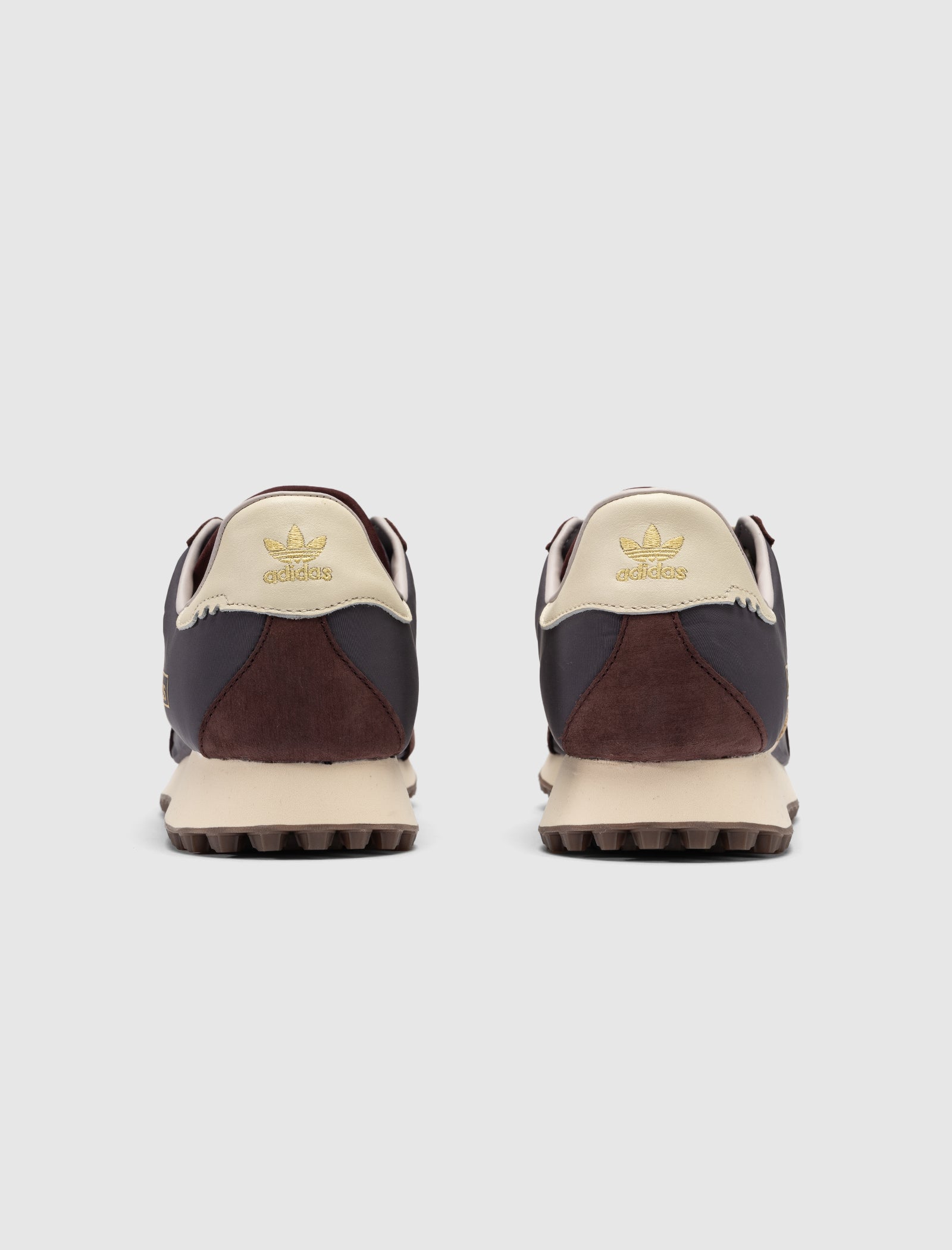 The DND BW RUN HARLEM'S BEST sneakers by Adidas, viewed from the back, feature cream-colored heels with gold logos, dark brown sides, and textured brown heels against a plain light gray background.