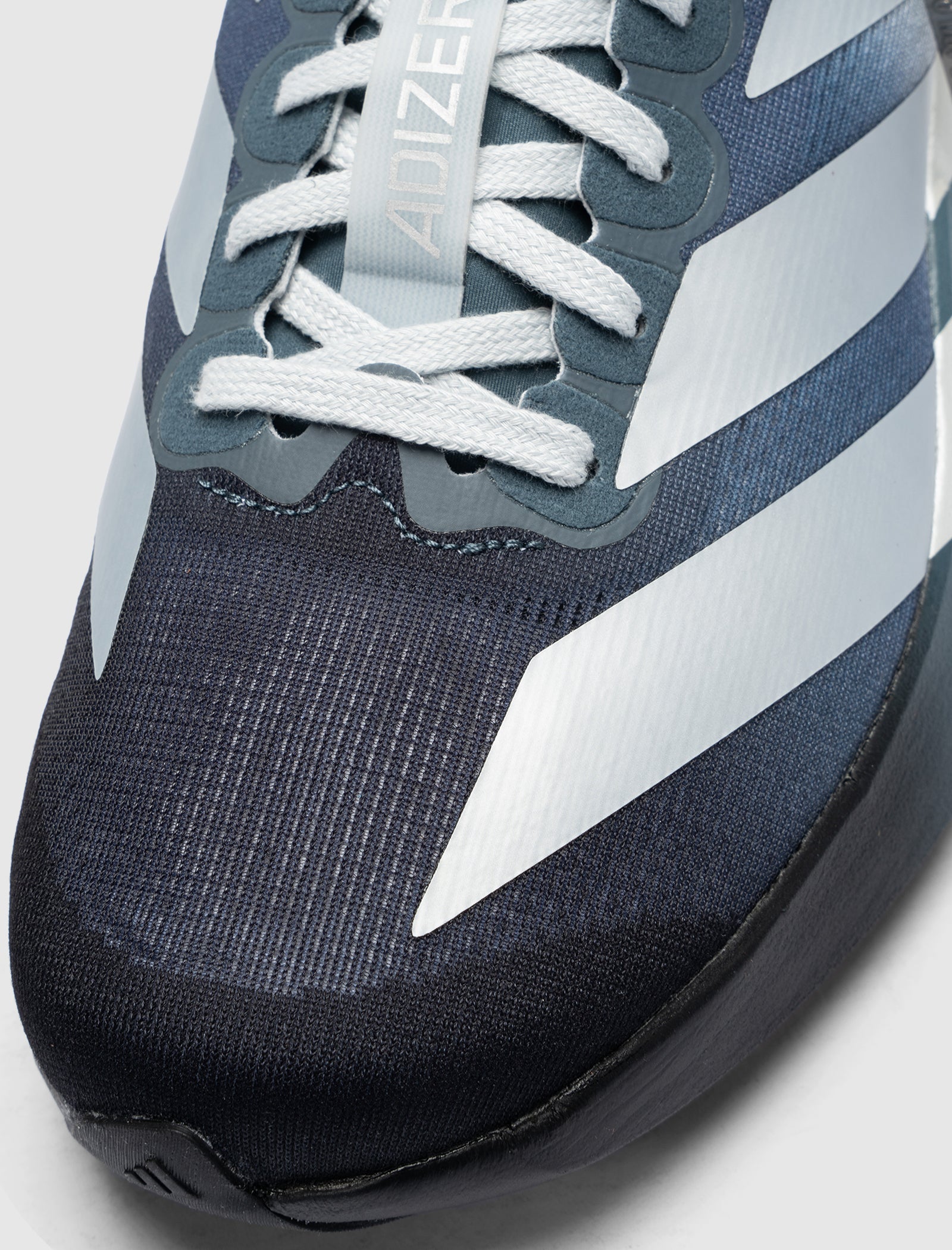 Close-up of the toe and laces of the DO NOT DUPLICATE EVO SL DAYGLOW "BLACK/BLUE/CLAY" sneaker, featuring lightweight mesh for breathability and distinctive white stripes on the side.