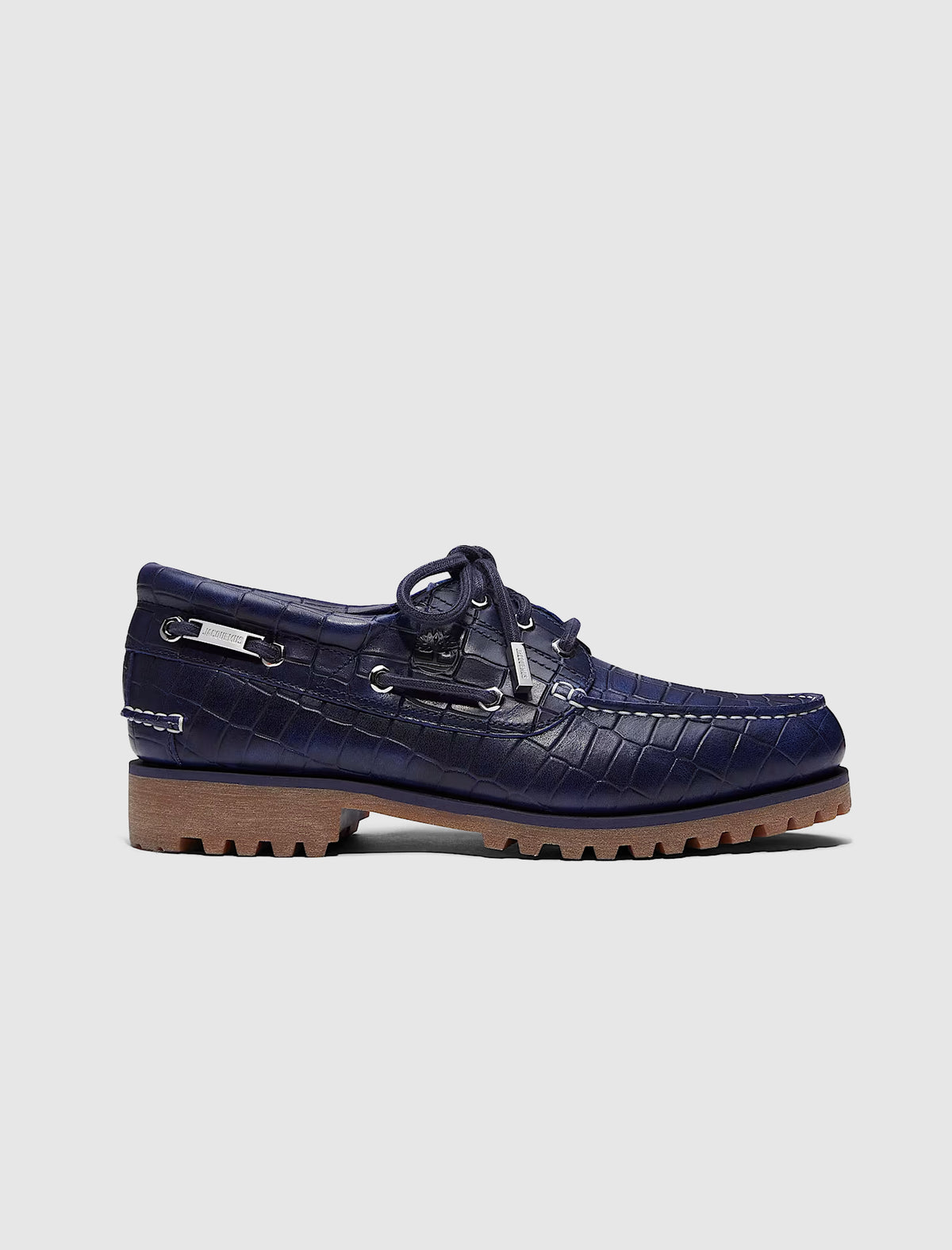 TIMBERLAND X JACQUEMUS 3 EYE BOAT SHOE in navy blue crocodile-embossed leather with silver hardware and a thick tan lug sole.