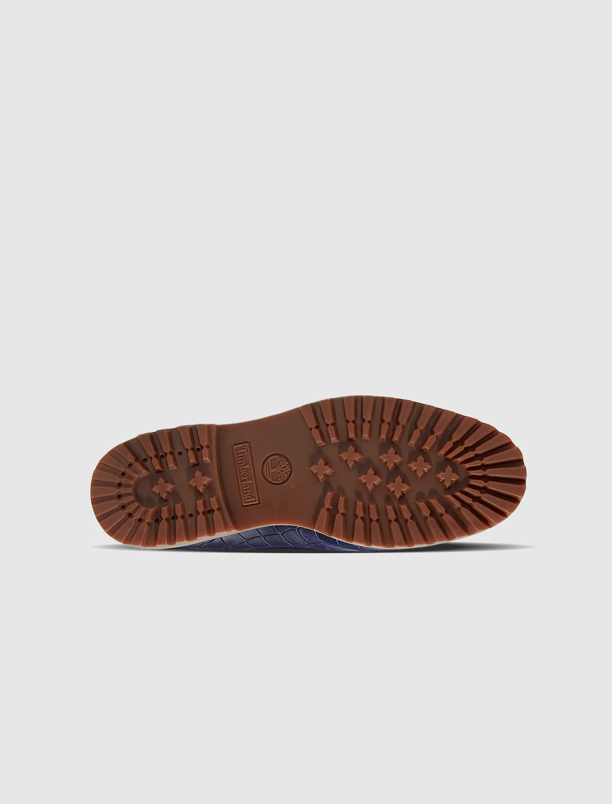 The textured navy blue sole of a TIMBERLAND X JACQUEMUS 3 EYE BOAT SHOE featuring a brown rubber lugged outsole.