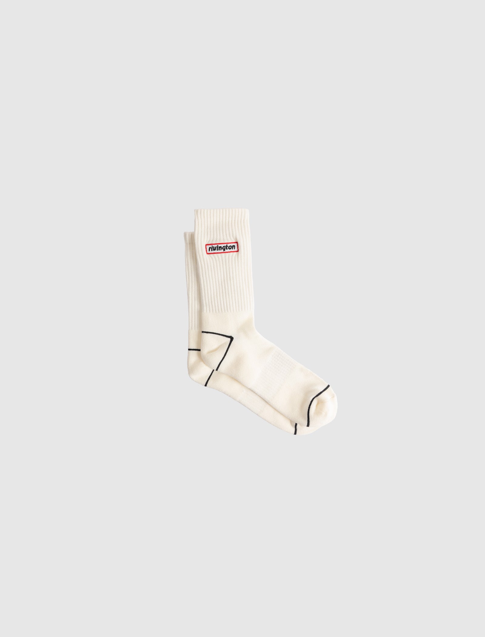 A single RIVINGTON SOCK in cream cotton with thin black lines and a small red and white rectangular ninjinon logo patch on the side, shown on a plain light gray background.