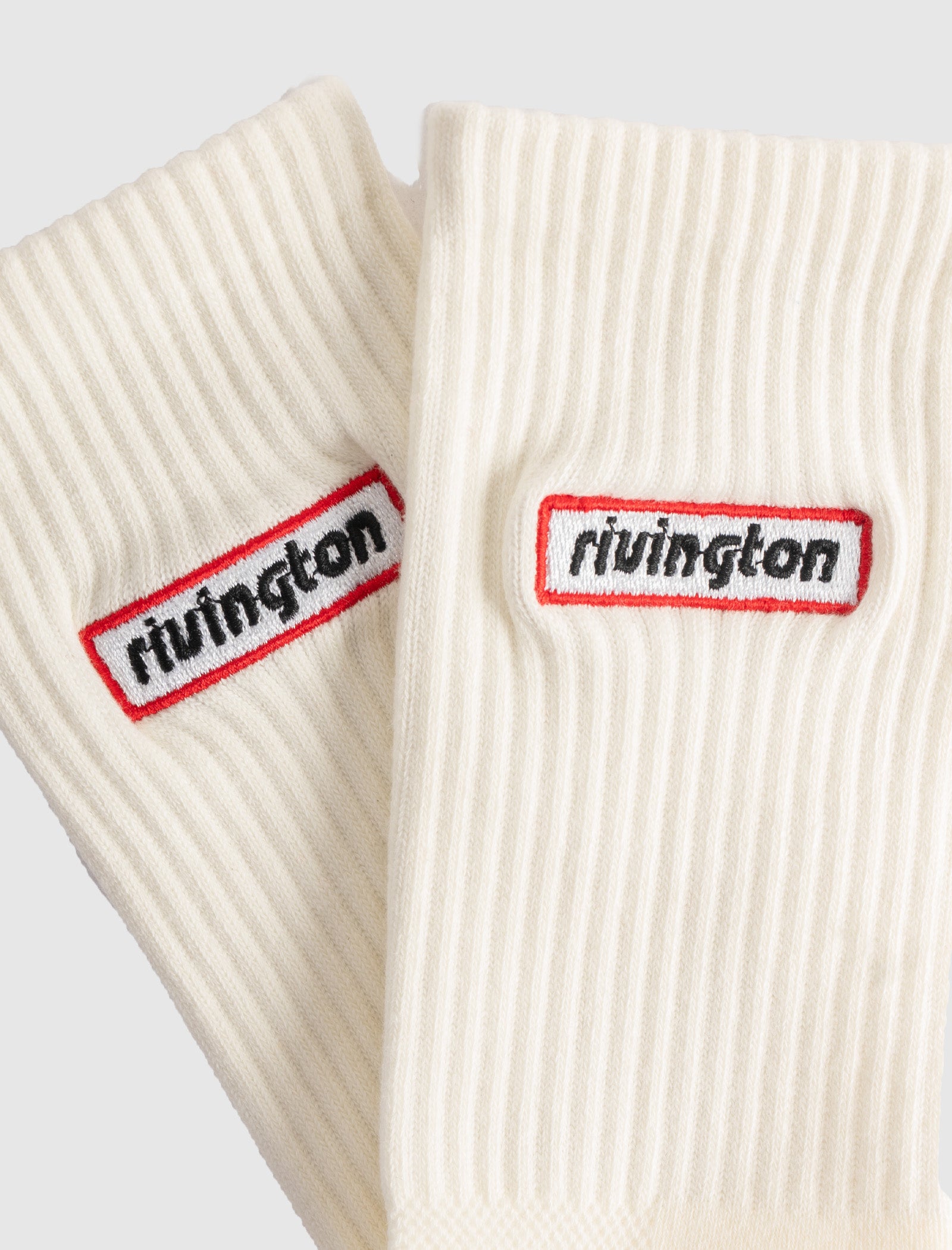 The RIVINGTON SOCKS are off-white ribbed crew socks with a red-outlined rectangular patch embroidered with 